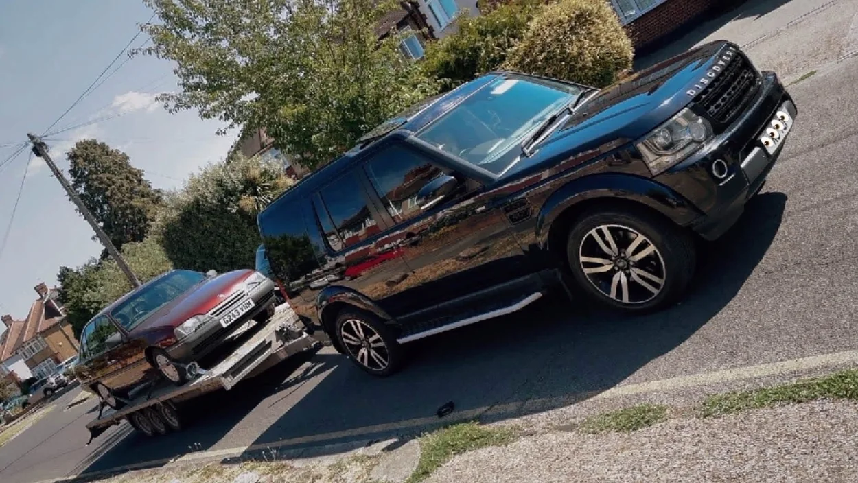 Land Rover Discovery towing a recovery trailer with a car